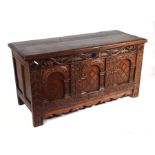 An 18th century oak coffer, the three-panel front heavily carved with leaves, Gothic type arches and