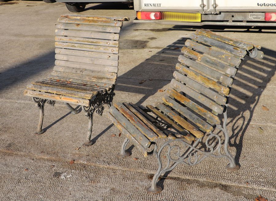 A pair of cast iron garden chairs with slatted wooden seats, each 62cms wide (wooden slats a/f) (