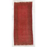 A Persian Turkoman hand knotted woollen runner with three rows of repeating guls, on a red ground,