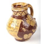 A Bideford glazed slipware harvest jug with motto and flower, bird and insect decoration, dated