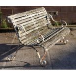 A slatted wooden garden bench with wrought iron scroll arms and feet, 153cms wide.