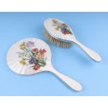 A silver and enamel hand mirror decorated with flowers; together with a matching hair brush,
