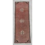 A Persian hand knotted woollen runner with three central guls within a repeated stylised design,