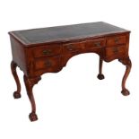 A George II style walnut kneehole writing table with an arrangement of five drawers on shell