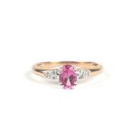 A yellow metal dress ring set with an oval pink stone and diamond set shoulders, approx UK size 'P',