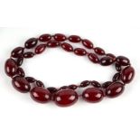 A strand of graduated cherry amber Bakelite beads with good swirl, largest bead 28mm long, 63g.