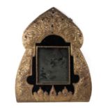 A Russian repousse brass wall mirror set with glass cabochons depicting Slavic birds and town