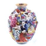 A Chinese Loughan porcelain snuff bottle decorated in relief with a multitude of figures, red four