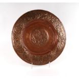 An Arts & Crafts copper dish with central knot decoration within a flowering scrolling foliage