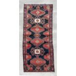 A Persian Hamedan hand knotted woollen runner with repeat geometric design on a beige ground, 310 by