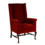 A George II style upholstered wing back armchair with cabriole front legs and turned stretchers.