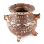 A South American tribal pottery tripod pot with animal mask handles and feet, decorated with a