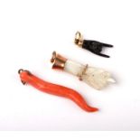 Two Victorian Grand Tour yellow metal charms in the form of hands, together with a pink coral