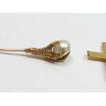 A talon clutching a pearl stickpin, the pearl unte