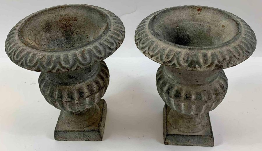 A pair of cast iron urns, each with reeded decorat