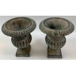 A pair of cast iron urns, each with reeded decorat