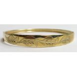 A 9ct gold graduated hinged bangle with foliat