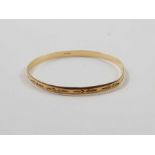 A 9ct gold solid bangle, engraved decoration throu