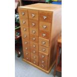 A light oak filing cabinet of 24 small drawers arr