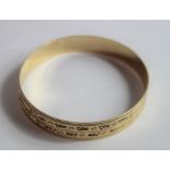 A 9ct gold solid bangle, flat profile with pattern