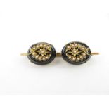 A bar brooch set with two seed pearl mounted black