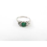 An emerald and diamond three stone ring, the white