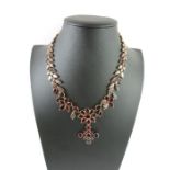 A flat cut garnet necklace with a cruciform pendan