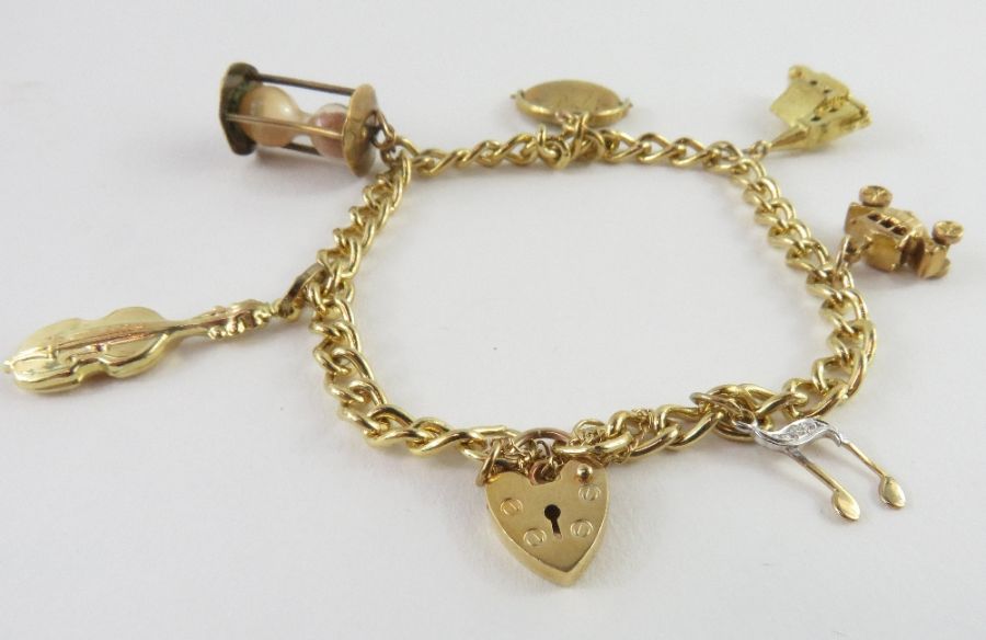 A curb link charm bracelet stamped '375', with hea