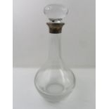 A plain glass decanter, with silver collar, bears