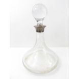 A plain glass ships decanter, with silver collar,