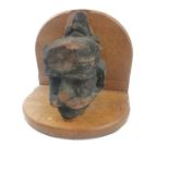 A carved stone Gothic head, on a modern oak base