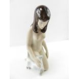 A ceramic figure of a nude female stroking a cat,