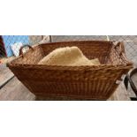 Large wicker basket with handles and sheepskin rug