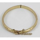 A 9 carat gold hinged bangle, with facetted decora