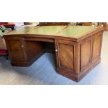 A 20th century curved mahogany desk with three gre