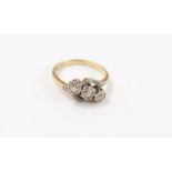 A three stone diamond cross over ring, stamped ‘18
