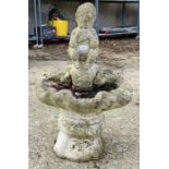 A stone figure playing pipes birdbath