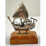 A silver model of a Chinese 'junk' boat, with arti