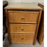 A vintage rattan bedside cabinet, of three short d