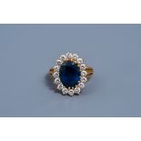 An 18 carat yellow gold ring set with a blue sapphire and sixteen diamonds, 20th C.