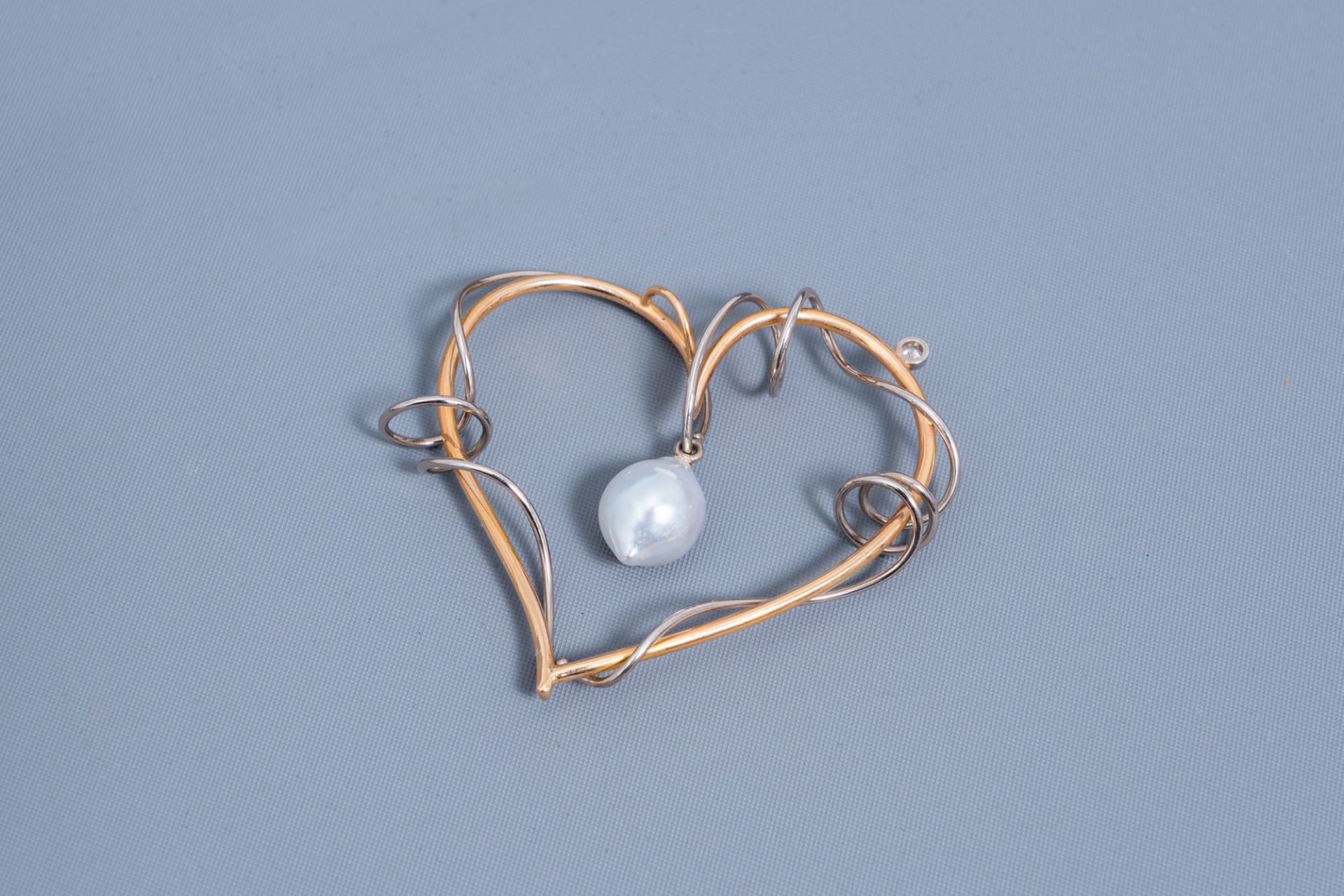 An 18 carat white and yellow heart-shaped pendant set with a diamond and a white South Sea pearl, 20