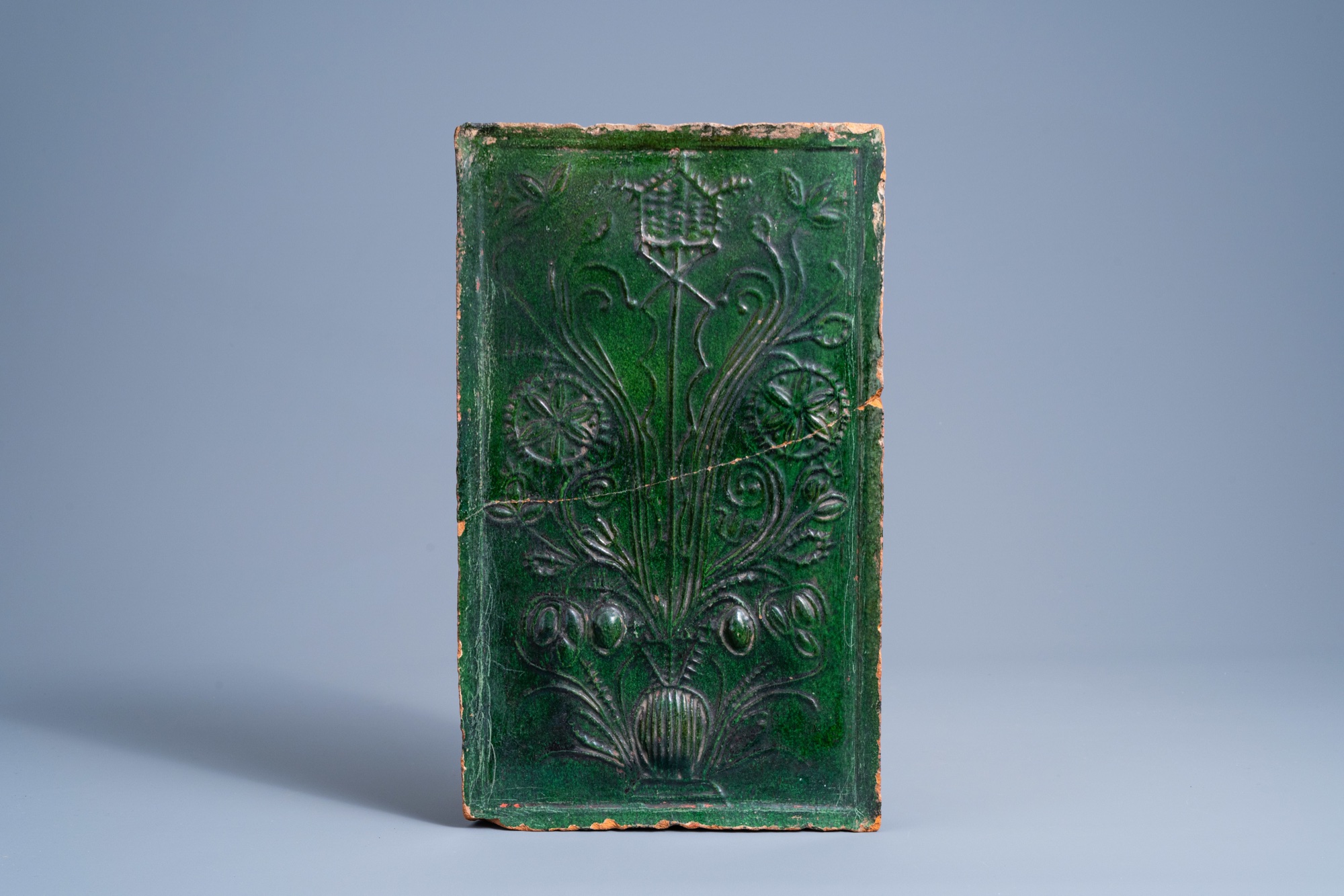 A German green glazed earthenware stove tile with floral design, 16th/17th C.