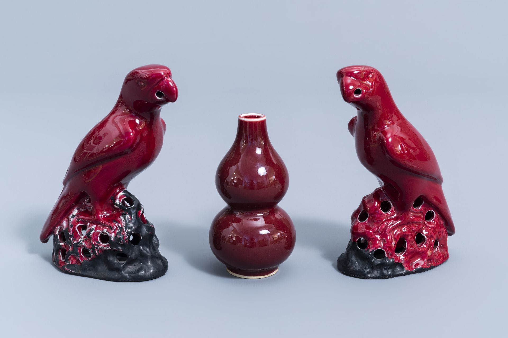 A pair of Chinese red glazed parrots and a monochrome red double gourd vase, 20th C.