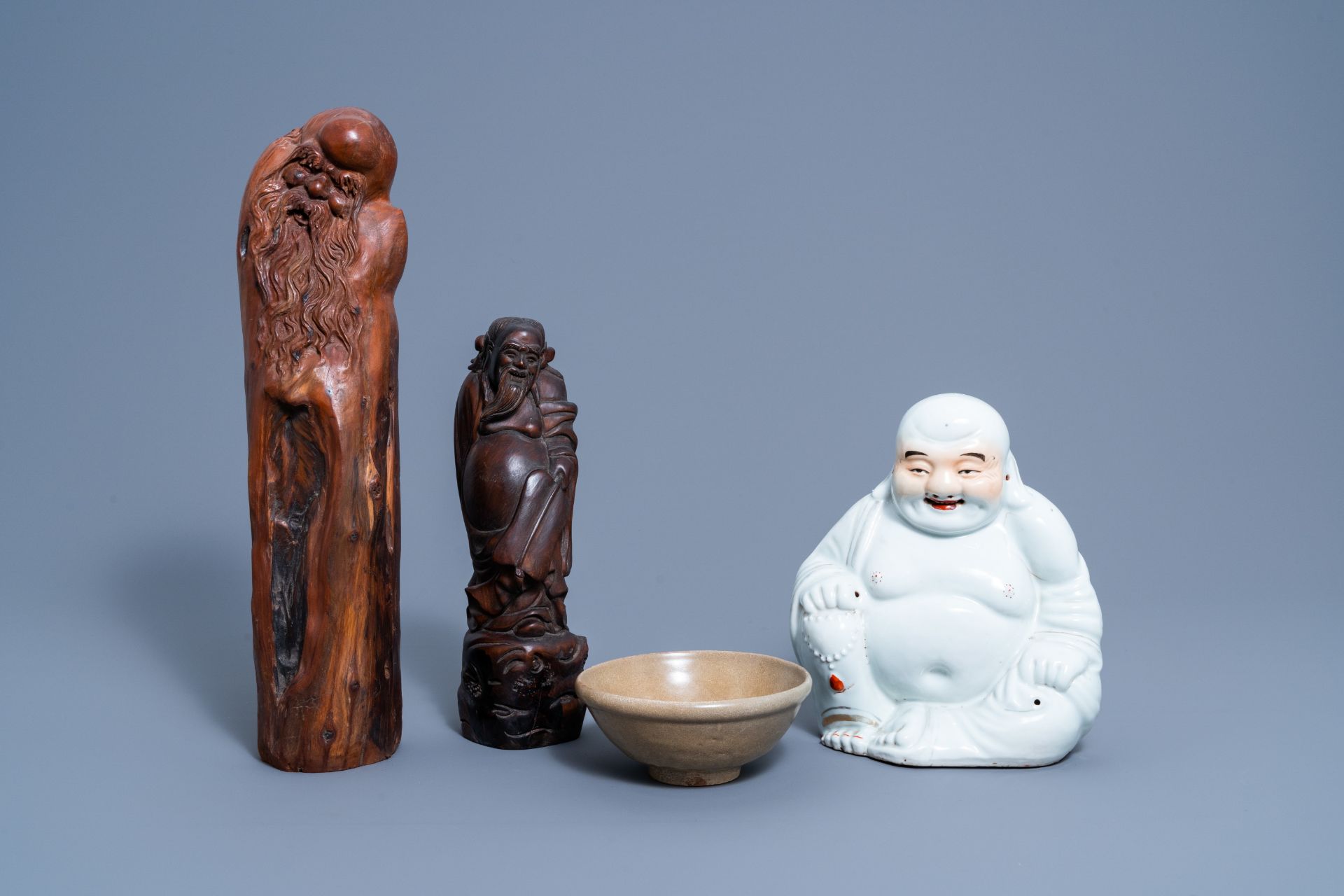 A Chinese white, iron red and gilt porcelain figure of Buddha, two carved wood figures and a celadon