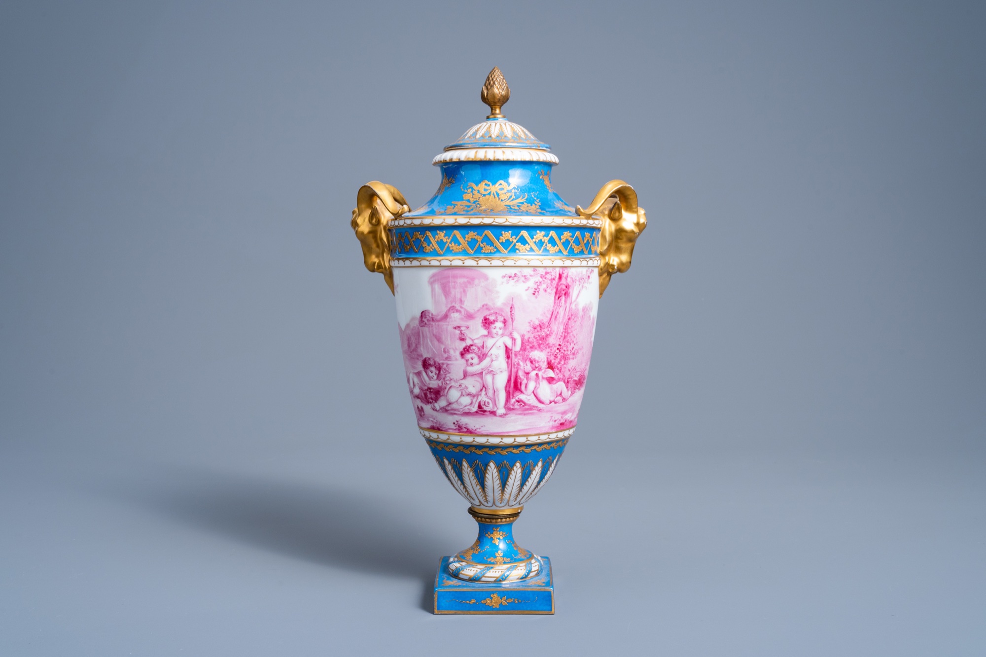 A French gold layered 'bleu celeste' ground vase and cover with putti in a landscape and ram's heads