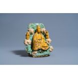 A Chinese sancai glazed earthenware group of a seated Buddha flanked by servants, Ming/Qing