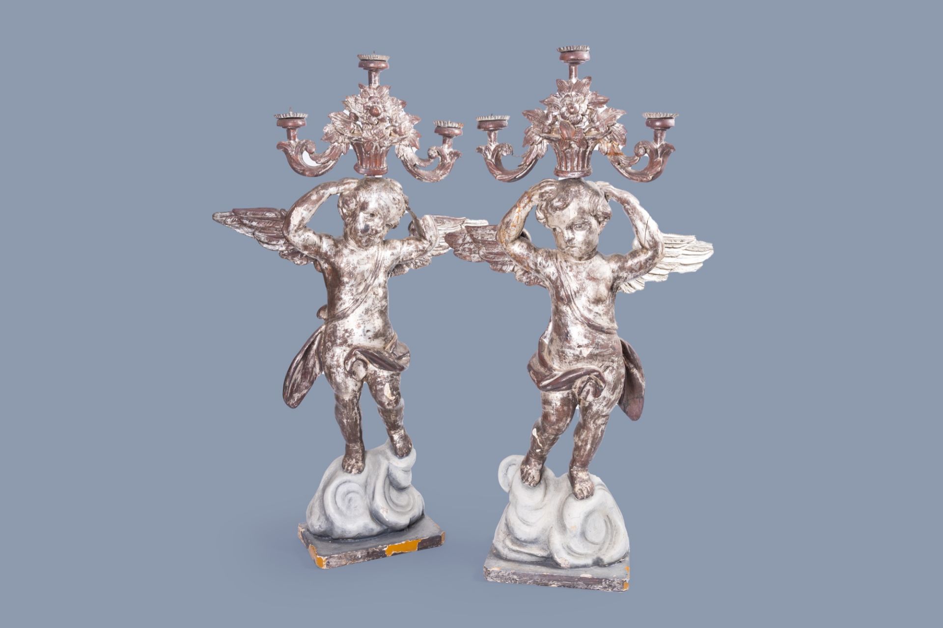 A pair of imposing Italian carved, polychrome painted and silver-plated wood angel shaped candlestic