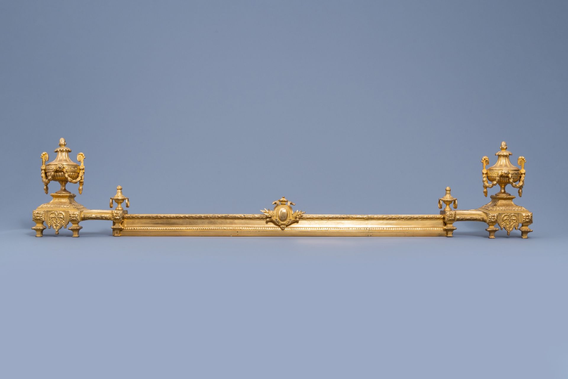 A pair of French Louis XVI style gilt bronze chenets and fire fender, 19th/20th C.