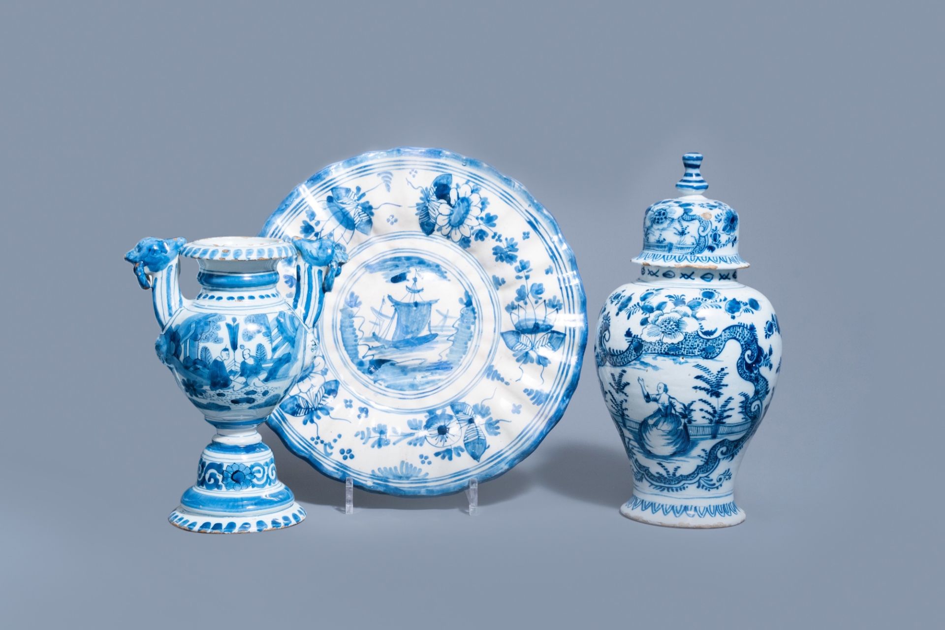 A Dutch Delft blue and white gadrooned dish with a boat and two vases with figures in a garden, 17th