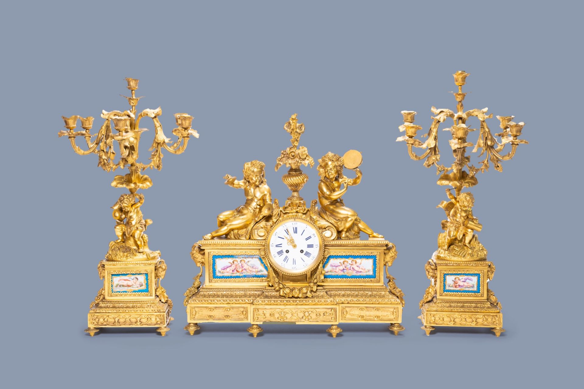 A French gilt bronze three-piece clock garniture with musicians and Svres style plaques, 19th C.